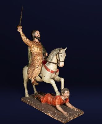 statue of a man on a horse with a sword and a man laying on the ground