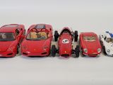 five toy cars lined up in a row on a white surface