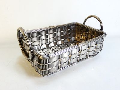 un panier en métal muni d'une poignée, posé sur une table blanche