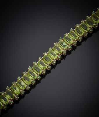 un gros plan d'un bracelet orné de pierres vertes sur fond noir