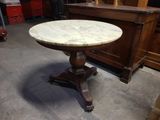 une table au plateau en marbre et au piètement en bois, dans une pièce