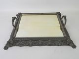 an ornate silver tray with a mirror on it on a white surface