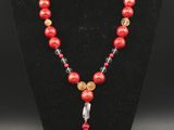 a red beaded necklace with a tassel on a black mannequin