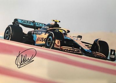 photo dédicacée d'une voiture de course sur un circuit, avec le ciel en arrière-plan