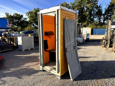 an outhouse with a door open in a parking lot