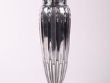 un vase en argent posé sur une surface blanche