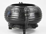 a black pot with a bird on it on a stand