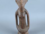 un gros plan sur une statue en bois représentant une personne, sur fond gris