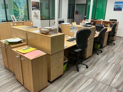 de nombreux bureaux et chaises dans un bureau doté d'une grande fenêtre