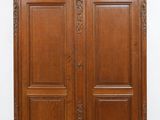 une grande armoire en bois à deux portes, avec un dessus sculpté