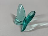 a green glass butterfly sitting on a white surface