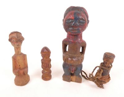 Trois figurines en bois sont assises les unes à côté des autres sur une surface blanche