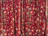 red curtain with floral pattern hanging on a wall next to a window
