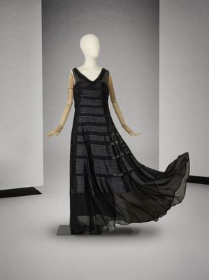 une photo d'un mannequin portant une robe noire dans une pièce blanche