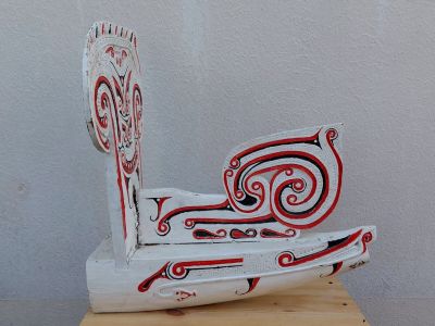 une sculpture en bois représentant un bateau, posée sur un socle en bois