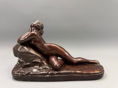 une statue en bronze représentant une femme allongée sur un rocher