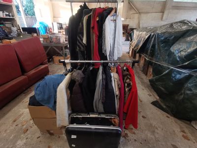 une photo d'une chambre avec une valise et des vêtements suspendus à un portant