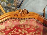 a red and gold couch with gold trimmings and a mirror behind it