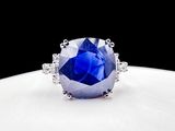 a close up of a blue sapphire and diamond ring on a white surface