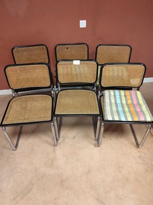 quatre chaises et une table dans une pièce, avec un mur en arrière-plan