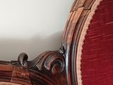 a cat sitting on a red chair in the corner of a room