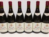 six bouteilles de vin rouge sont alignées sur une surface blanche