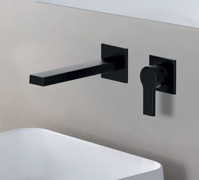 Le robinet noir est fixé au mur à côté d'un lavabo blanc.