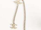 a chanel necklace with a chain and two charms on it