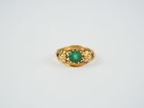 a close up of a gold ring with a green stone