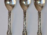 trois cuillères en argent sont alignées les unes à côté des autres sur une surface blanche