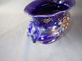 a purple vase with a gold decoration on it