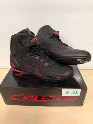 une paire de chaussures noires et rouges posée sur une boîte