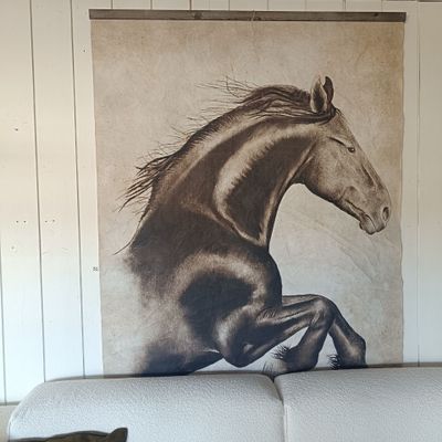 un chat assis sur un canapé devant une photo représentant un cheval