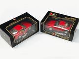 une paire de petites voitures rouges moulées sous pression, dans des boîtes noires sur fond blanc