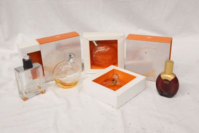 plusieurs flacons de parfum sont posés sur une surface blanche