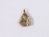 a close up of a gold pendant with a green stone in it