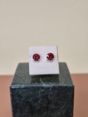 un gros plan sur une paire de boucles d'oreilles en rubis rouges posées sur un bloc de marbre