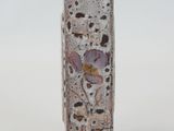 a small vase with a flower on it on a white surface