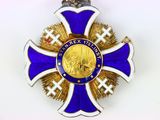 une croix violette et dorée sur laquelle est accrochée une médaille en or