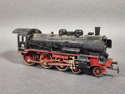 un train miniature noir et rouge posé sur une surface grise