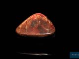 un gros plan d'une pierre rouge sur une surface noire