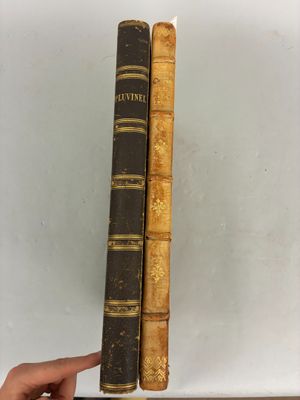 deux livres anciens posés sur une étagère, dont l'un est tenu par une main