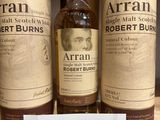 three bottles of whisky on a shelf in a store with a price tag