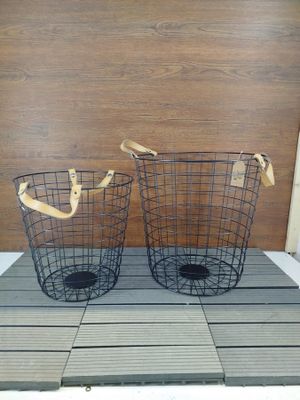 une paire de paniers en fil de fer avec des poignées en bois, posés sur un plancher en bois