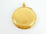 a small gold pocket watch on a white surface