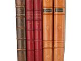 several old books are stacked on top of each other on a white surface
