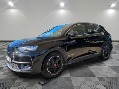 une voiture noire est garée dans une pièce au sol en damier