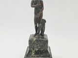 statue d'un homme accompagné d'un chien, posée sur un socle en marbre