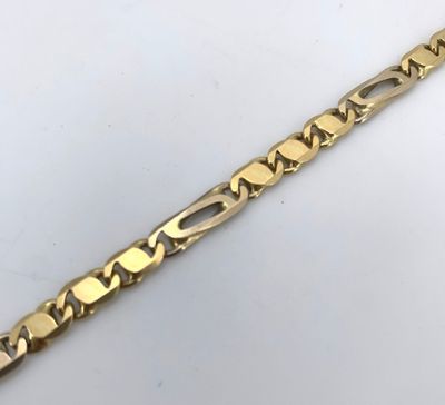 gros plan d'un bracelet en or sur une surface blanche