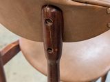 a close up of a wooden chair with a pink chair in the background
